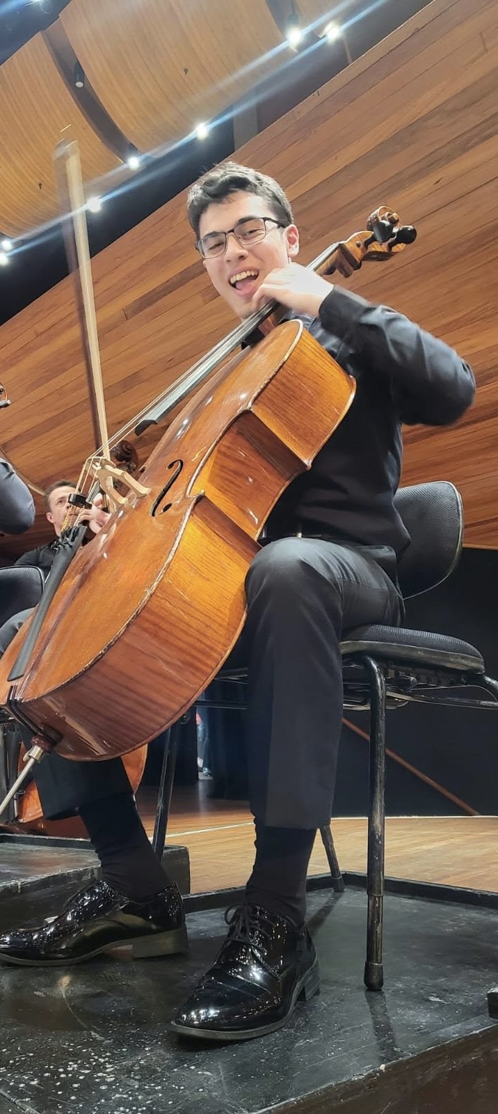 Benjamin Carter seated with his cello on stage