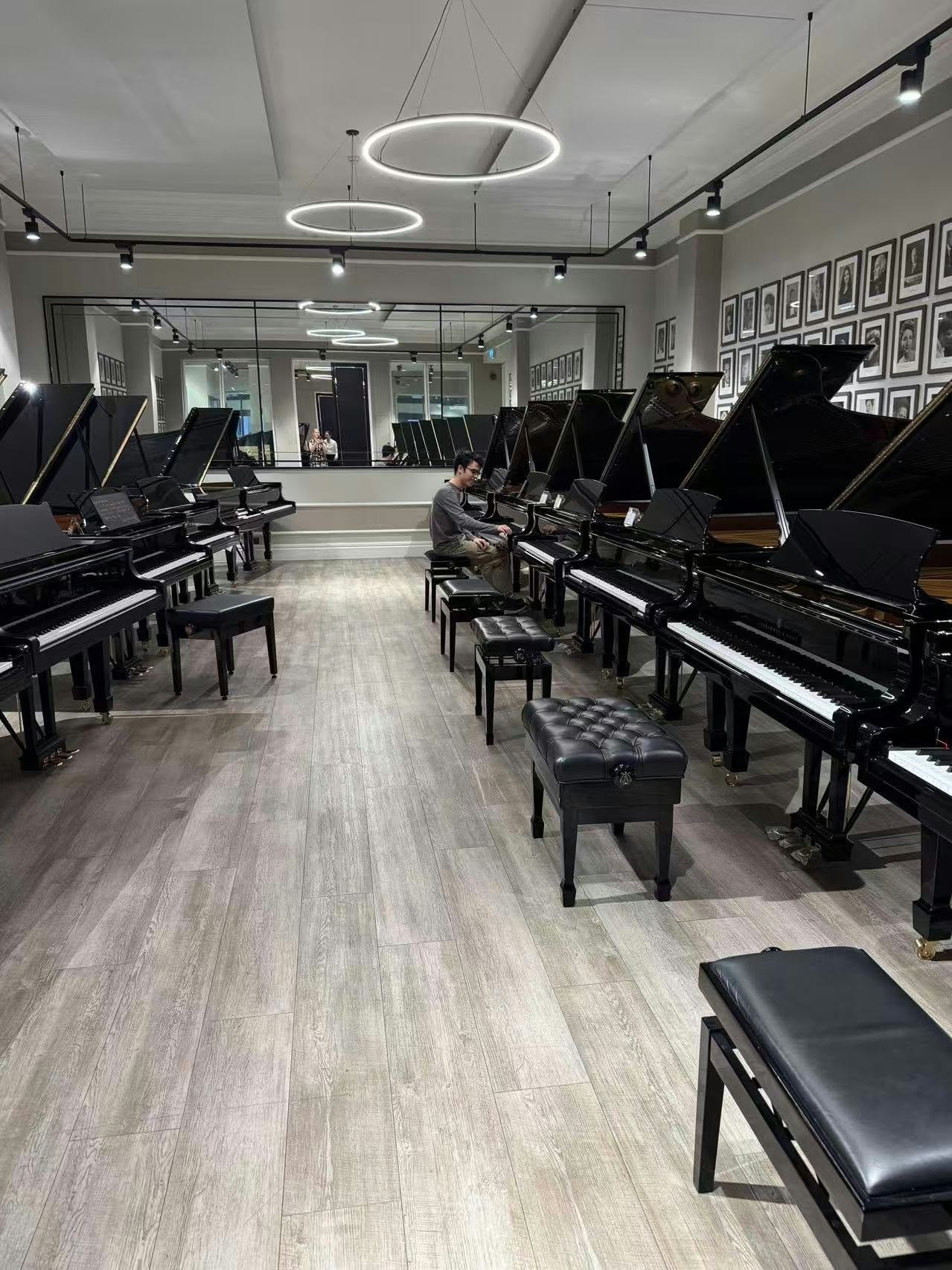 Benjamin Carter playing a grand piano in a room of pianos